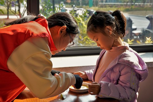 工作人员指导小朋友制作书签